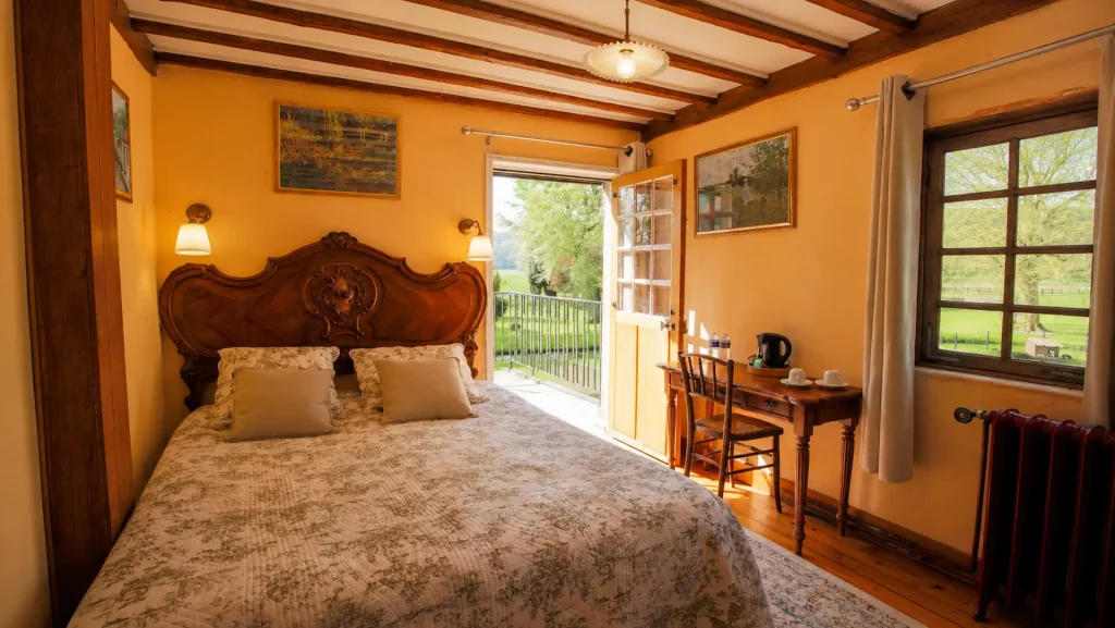 Chambre Cézanne aux poutres apparentes ouvrant sur le jardin, au Moulin des Chennevières à Giverny