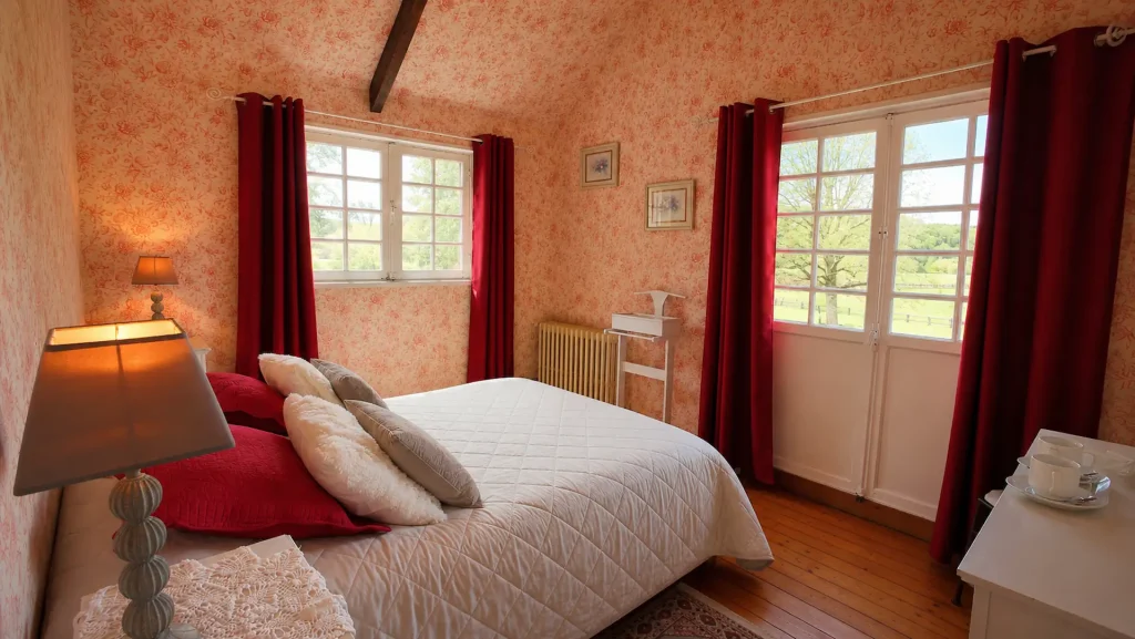 Chambre Pissarro aux tentures rouges et papier peint fleuri, au Moulin des Chennevières à Giverny