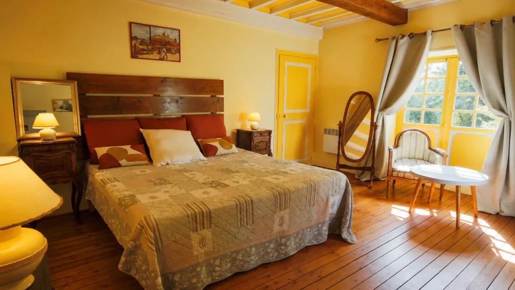 Chambre Renoir aux murs jaunes lumineux et poutres apparentes, au Moulin des Chennevières à Giverny